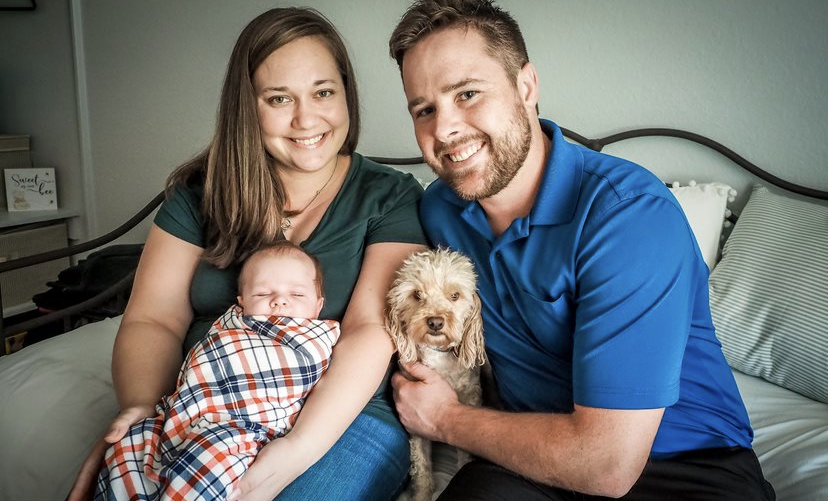 mom and dad holding infant and a small dog, a family photo